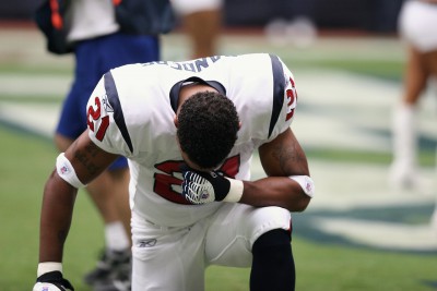 football player in uniform on field on one knee
