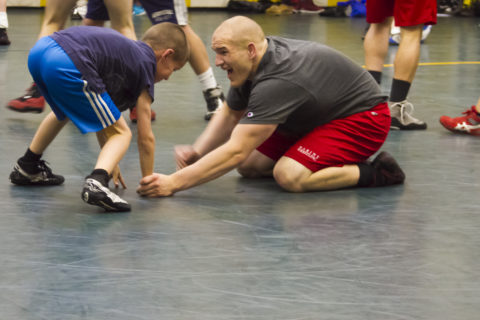 coach teaching kid wrestling
